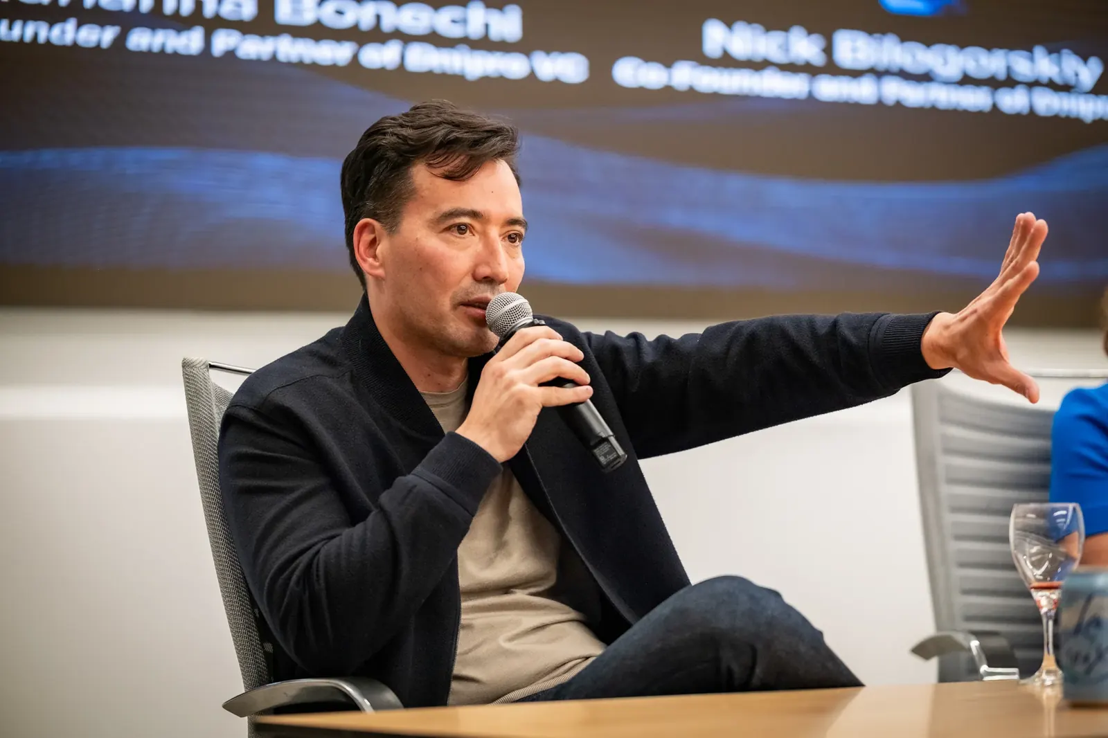 Speaker with a microphone extending one hand during a panel