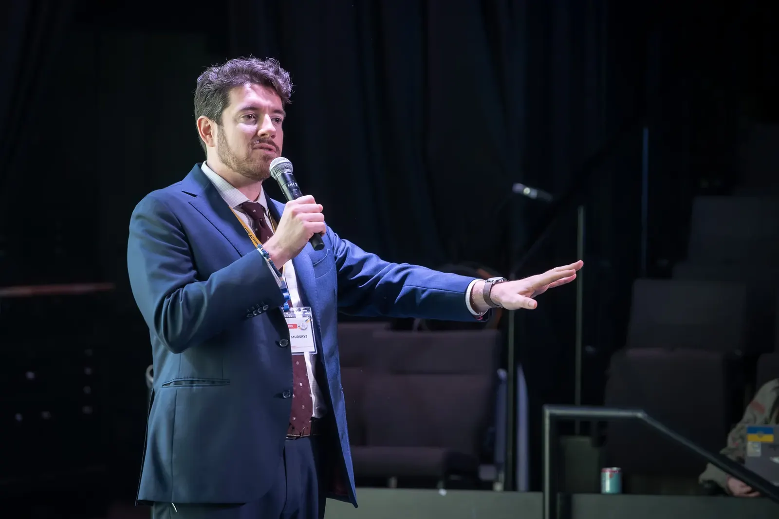 Speaker gesturing during a presentation on a dark stage